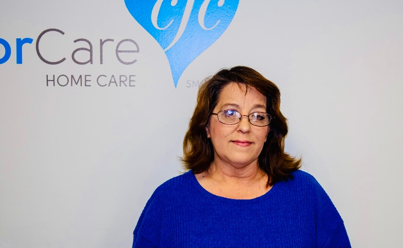 An in-home care nurse smiling next to the logo.